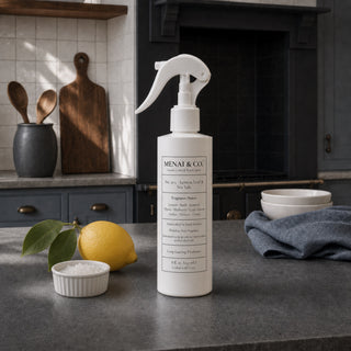 Lemon Leaf and Sea Salt linen and room spray styled in a kitchen with a fresh lemon, green leaves, and a small bowl of sea salt.