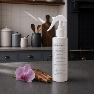 Wild Orchid and Sandalwood linen and room spray styled in a kitchen with a pink orchid bloom and sandalwood.
