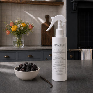 Black Raspberry and Vanilla linen and room spray styled in a kitchen with a bowl of black raspberries, a vanilla bean, and fresh flowers.