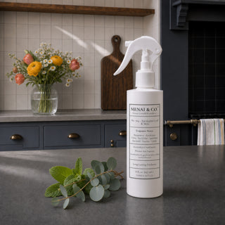 Eucalyptus Leaf and Mint linen and room spray styled in a kitchen with eucalyptus branches, fresh mint leaves, and flowers.