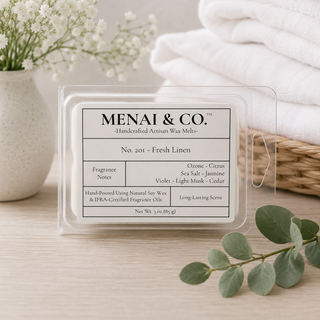 Fresh Linen soy wax melts in six-cavity clamshell beside folded white linens, eucalyptus stems, and soft white florals